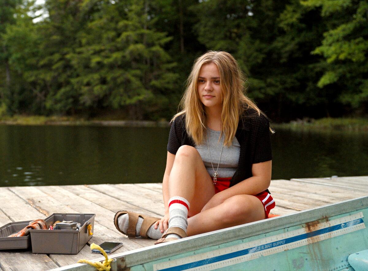 A woman sits on a boat dock.