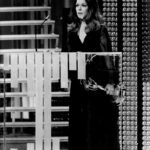 Treva Silverman stands behind a podium and holds an Emmy to her side.