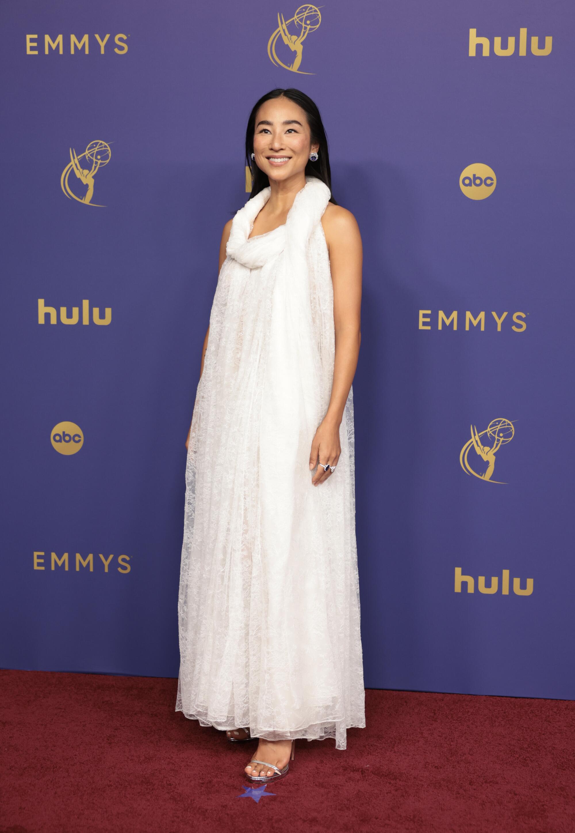 Greta Lee wears a white dress. 