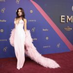 Eiza González wears a pink dress with a plunging neckline and feathered cape.