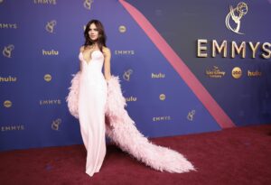 Eiza González wears a pink dress with a plunging neckline and feathered cape.