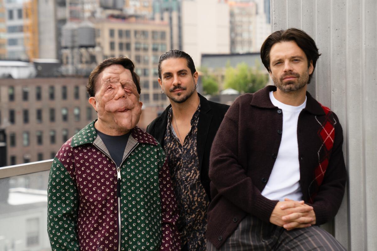 Three men pose on a rooftop deck.