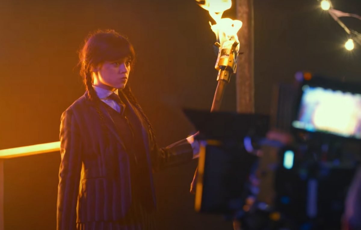 Wednesday season two behind the scenes with jenna ortega holding a torch