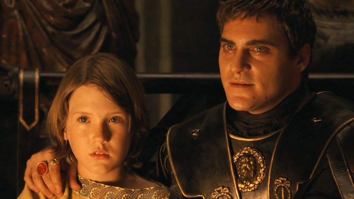 A scared young Lucius and a menacing Commodus with his arm on the boy's shoulder in Gladaitor