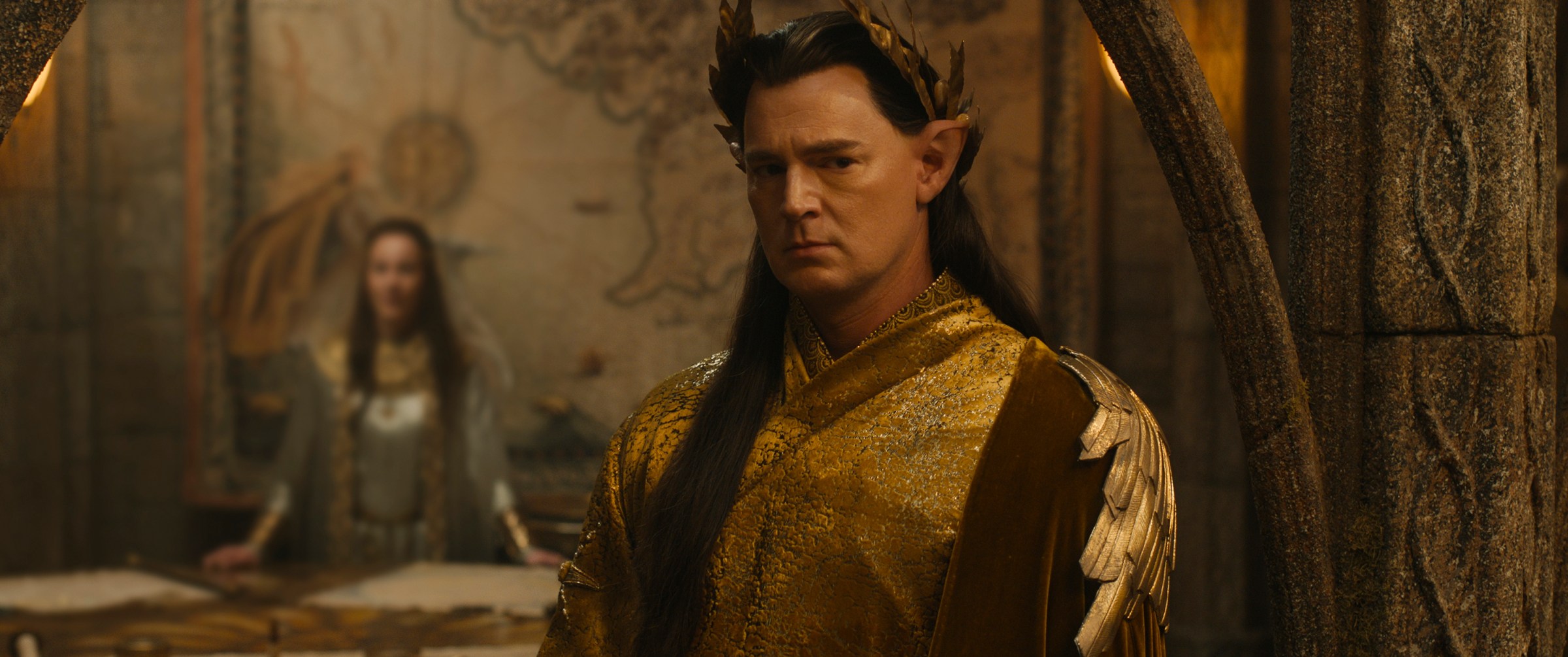 Elven High King Gil-galad (Benjamin Walker), a severe-looking, dark-haired elf in a crown, looks pensive in The Rings of Power