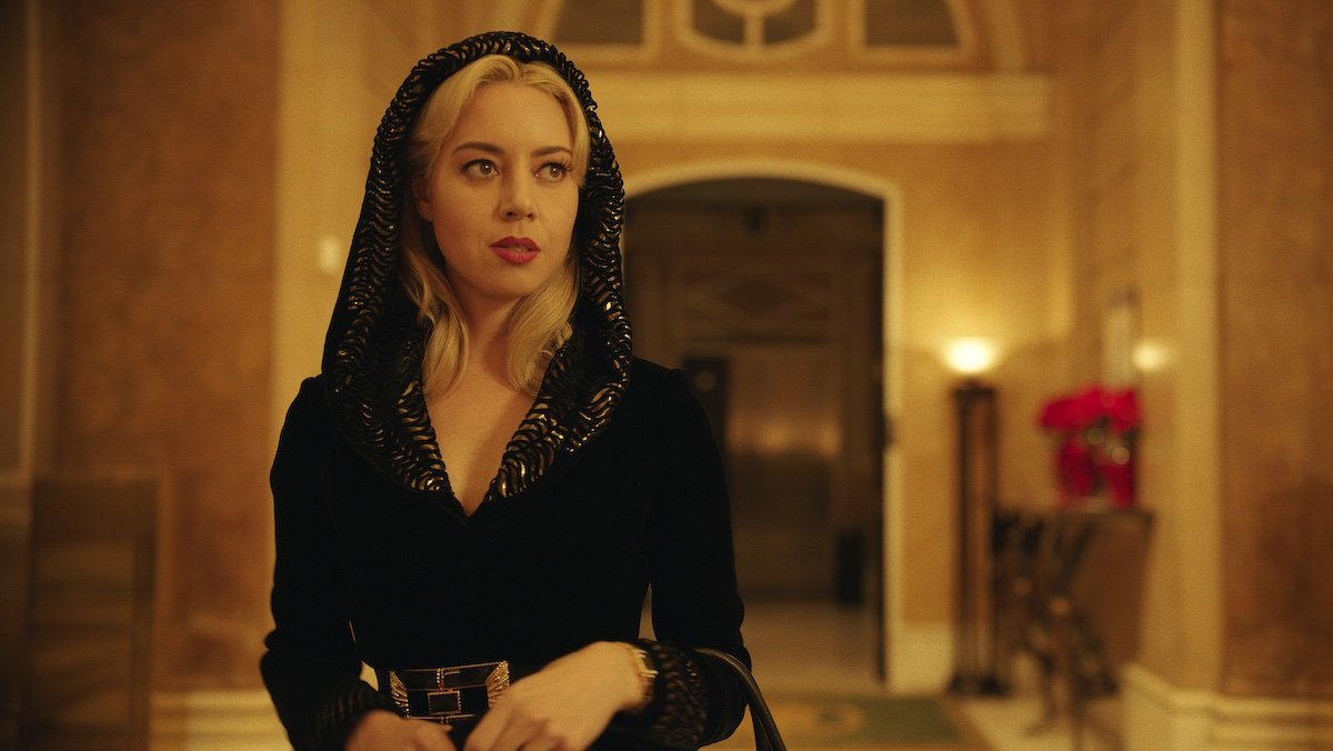 Aubrey Plaza with blonde hair draped in a black dress and robe in Megalopolis