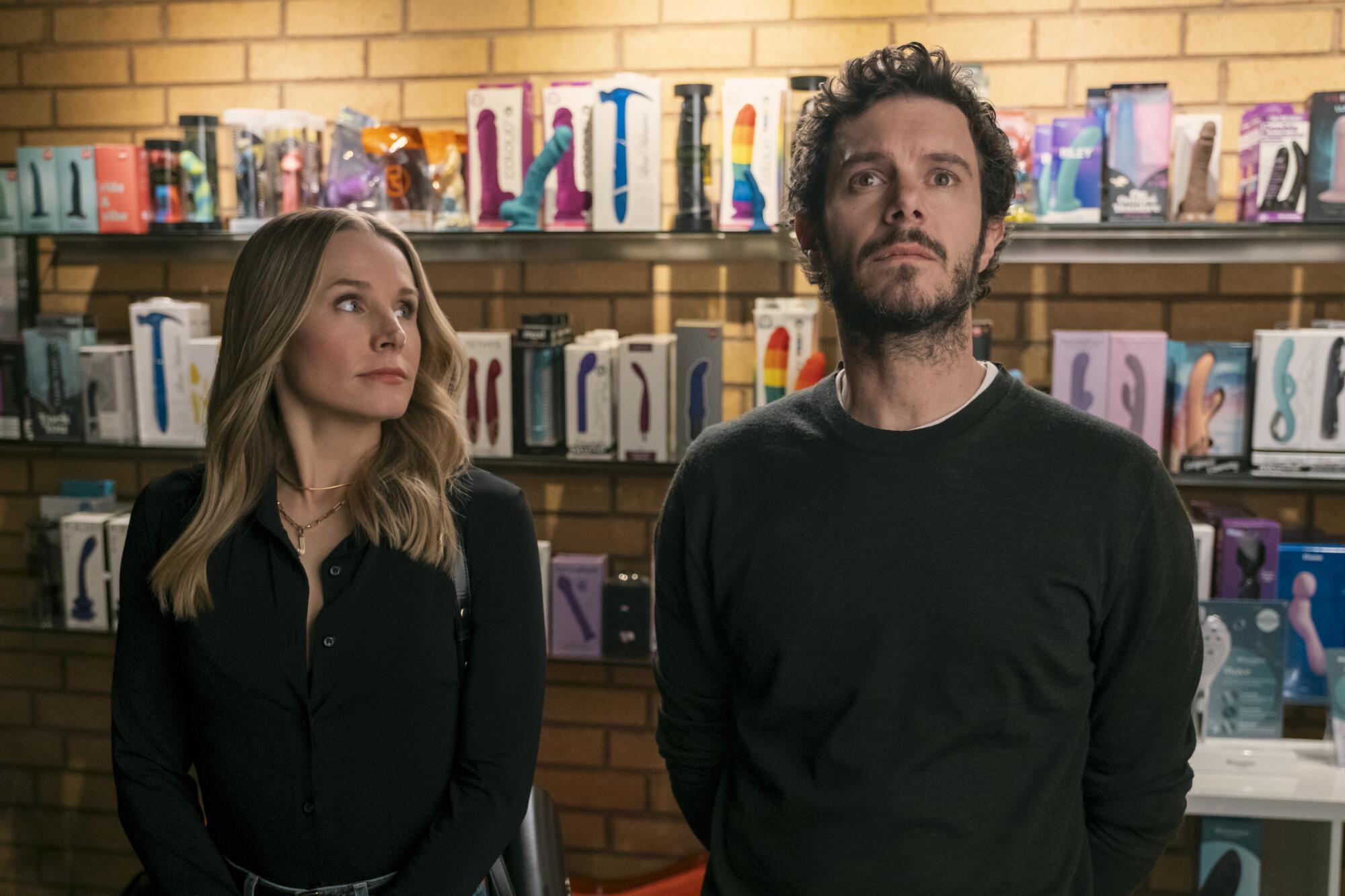 A man and a woman stand in a store before a display of vibrators.