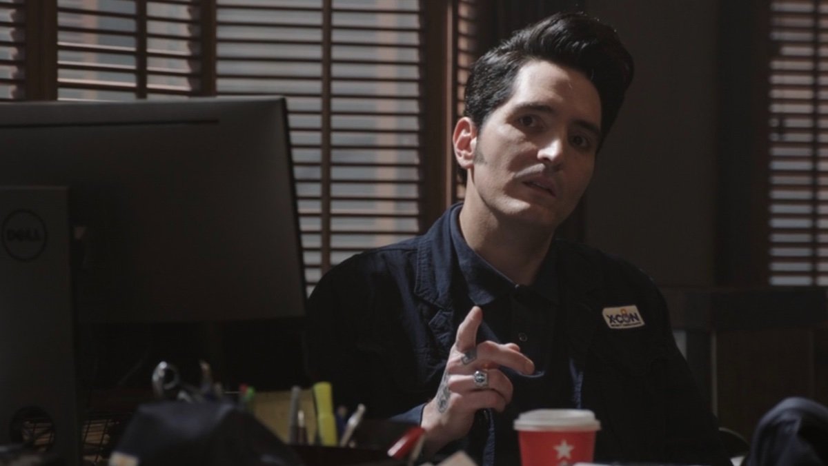 David Dastmalchian as Kurt holds up his finger behind a desk in Ant-Man and the Wasp