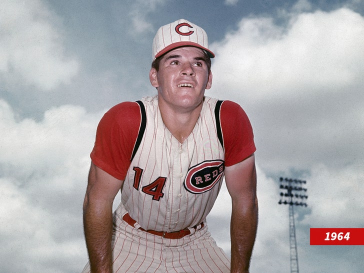 Pete Rose in a white pinstripe Cincinnati Reds uniform bent at the waste.