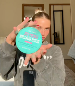 young woman holding up Trader Joe's Cacay Oil Body Butter