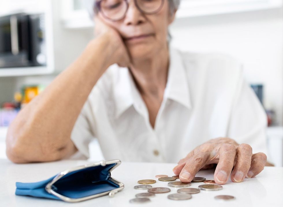 A senior woman counts change from her purse.