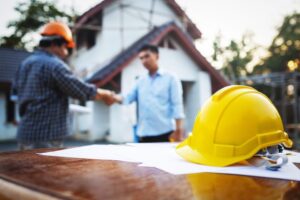 man shaking hands with a contractor outside his house