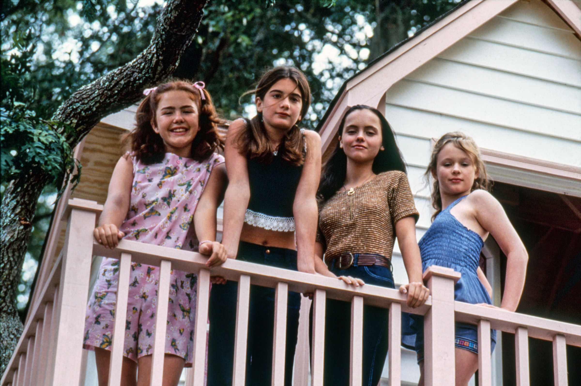 Four girls lean on the banister of a treehouse in Now and Then