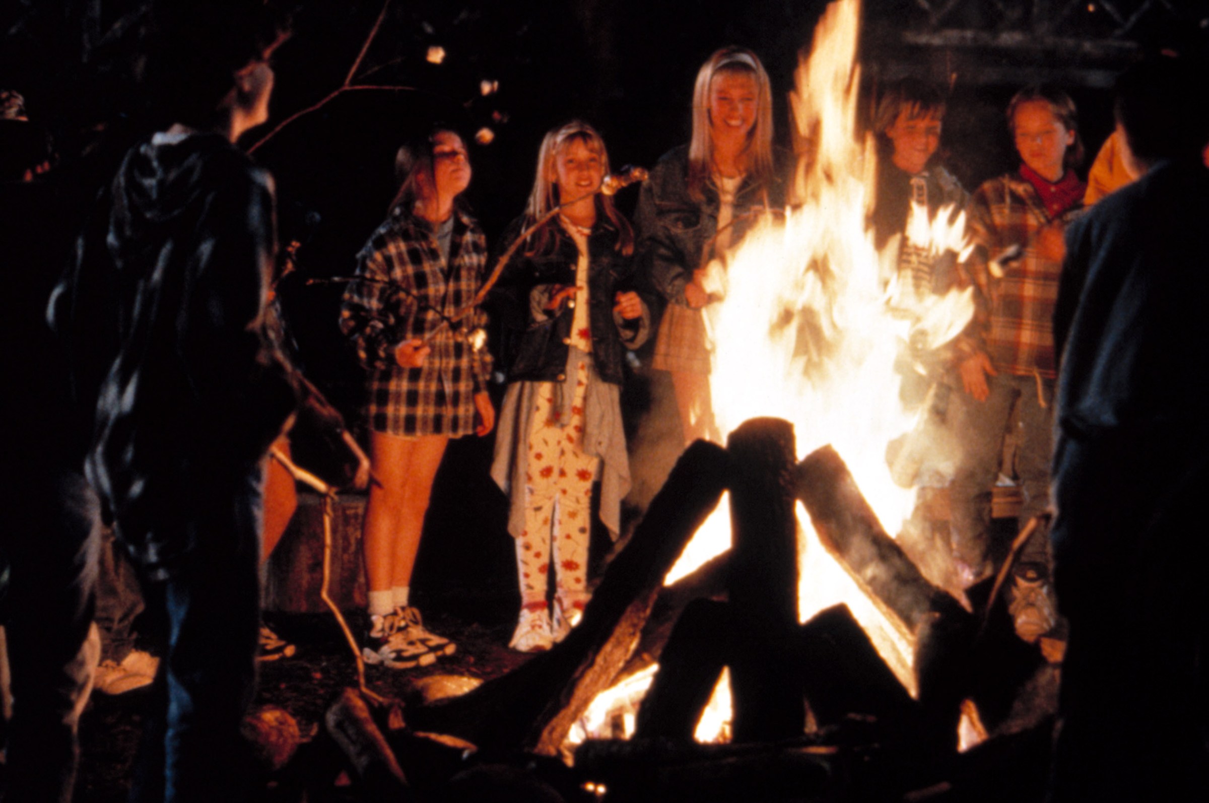 A group of teenagers and kids gather by a campfire in Camp Nowhere