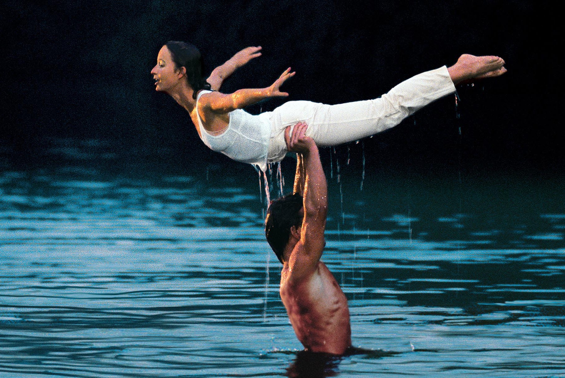 Patrick Swayze shirtless and wet in a lake, holding up Jennifer Grey above his head in Dirty Dancing