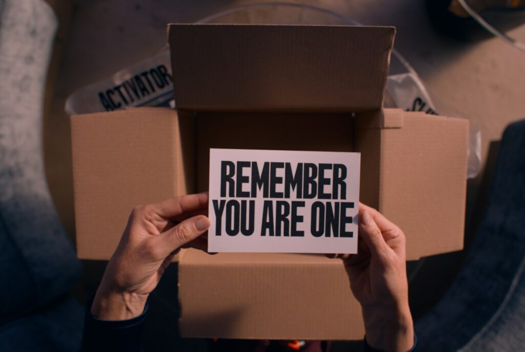 A shot from The Substance of Elisabeth holding the card from the package that says “REMEMBER YOU ARE ONE”