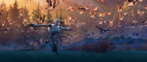 In a publicity still from The Wild Robot, a battered, bulbous white robot walks across a dark field with sunlight falling from above, holding her arms out to the sides as a flock of geese fly alongside her