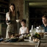 George MacKay, Mia Goth, and Charlie Heaton sit around a table in Marrowbone