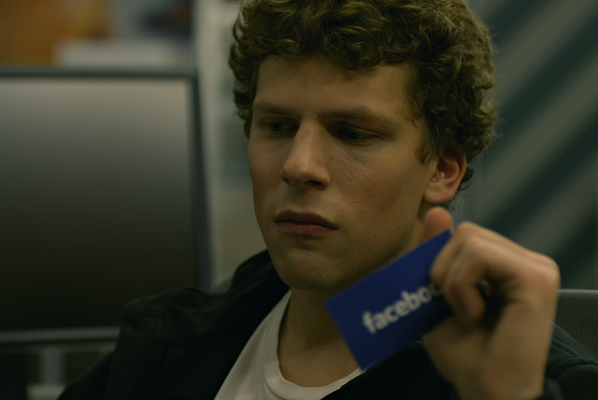 jesse eisenberg’s mark zuckerberg contemplates his business in a spinny chair while holding a Facebook business card in The Social Network