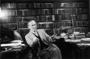 J.R.R. Tolkien in 1955, sitting in a library, surrounded by books