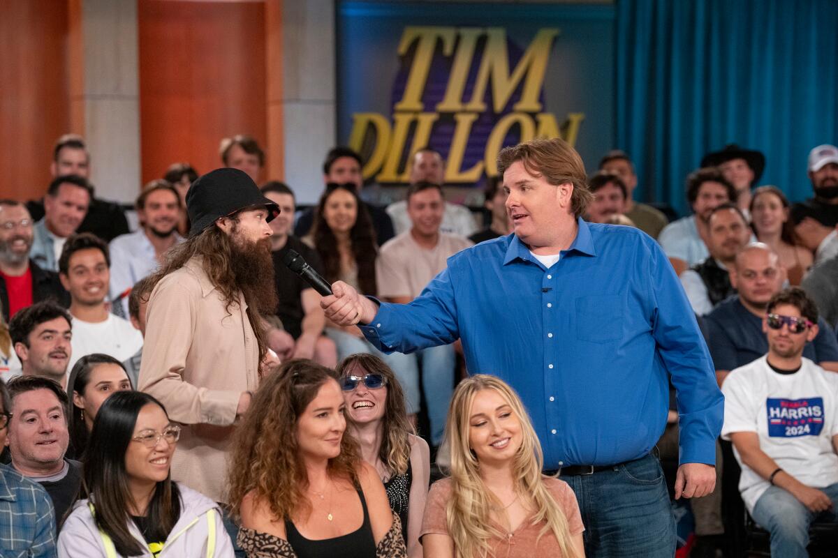 Man in a blue shirt holding a mic talking to an audience member