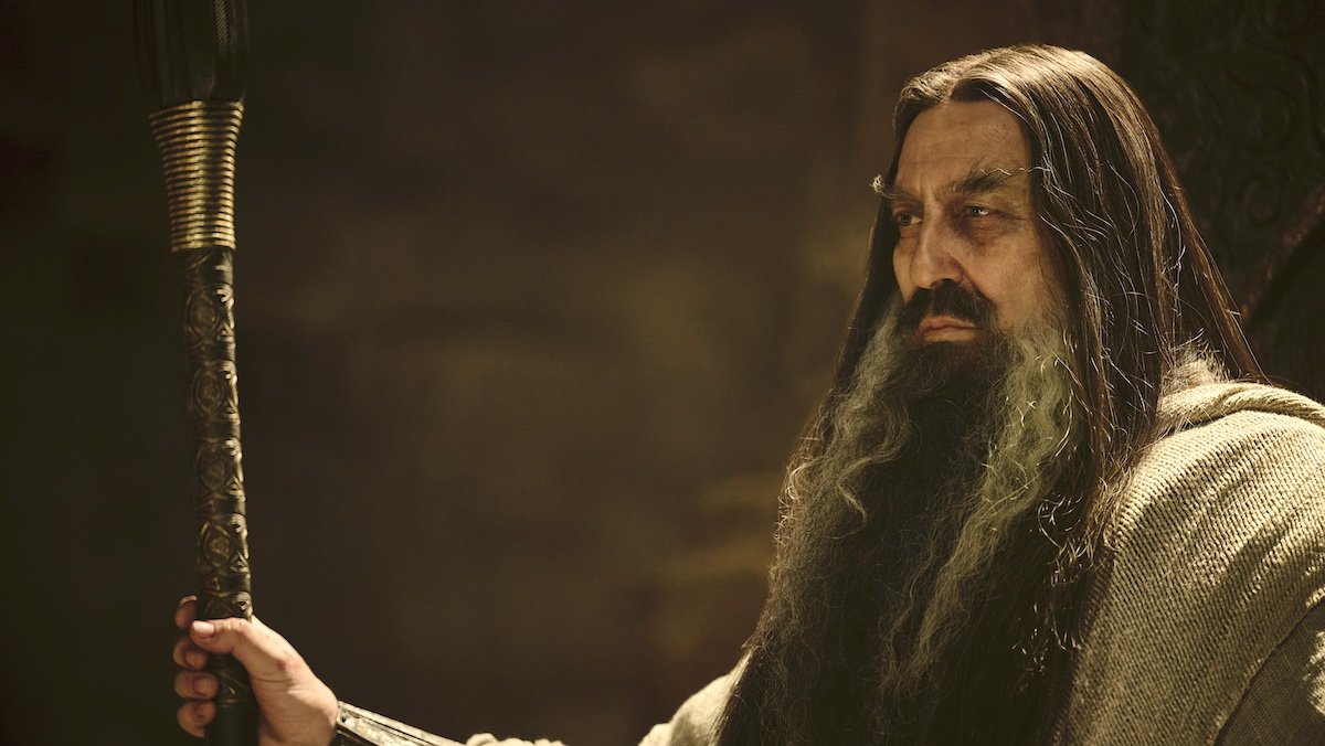 Ciaran Hinds with a long black and white beard holding a staff as a dark wizard on The Rings of Power