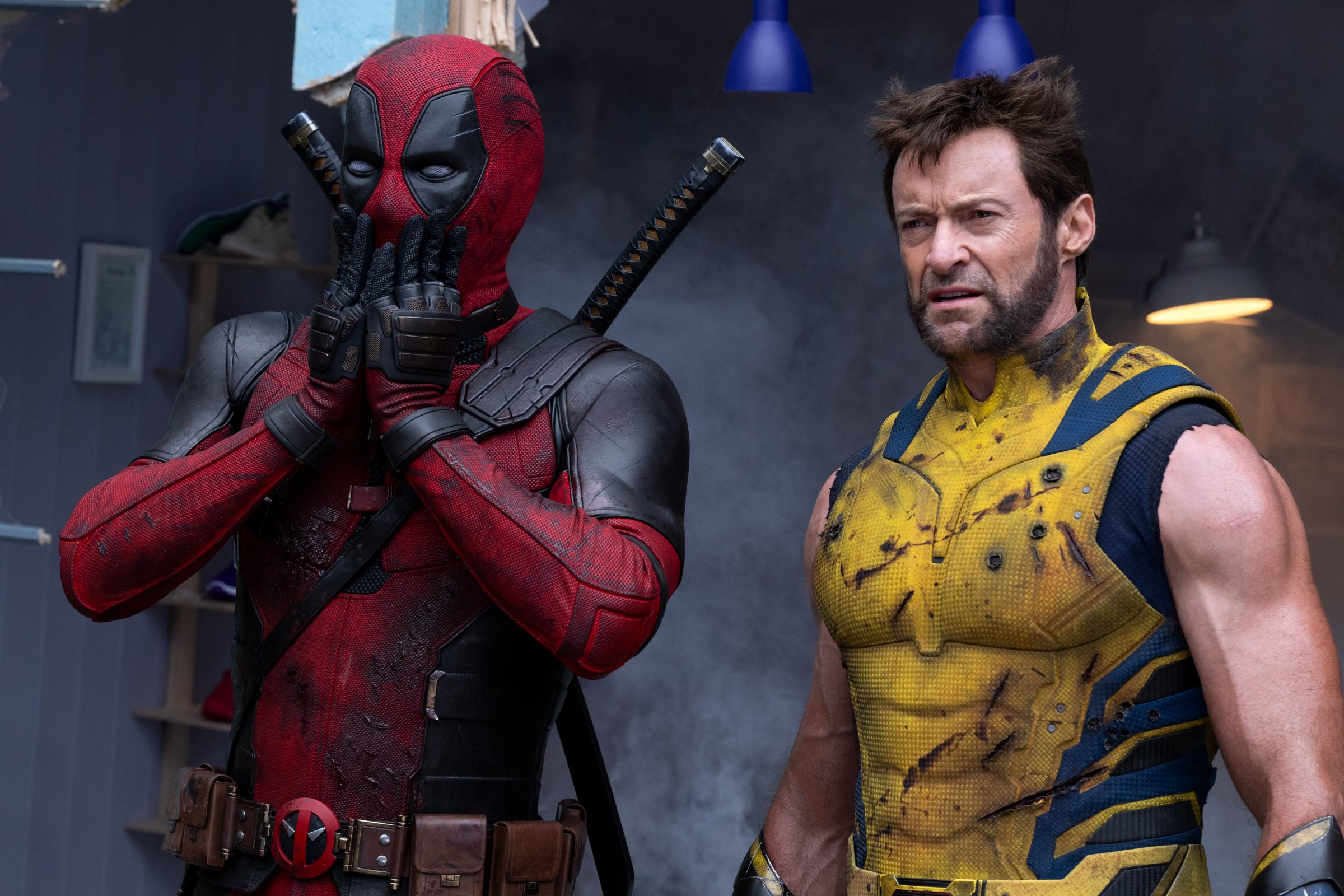 A battle-scarred Deadpool puts his hands over his mouth in shock as a beaten-up Wolverine looks weary beside him in a scene from the film Deadpool & Wolverine