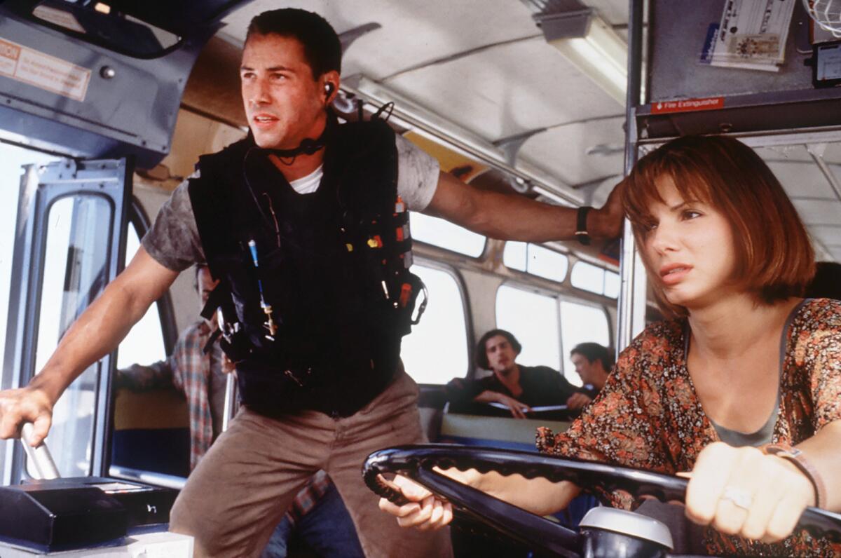 A cop stands in a bus driven by a woman.