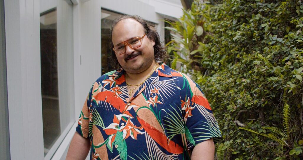 A man in a boldly patterned shirt smiles for the camera.