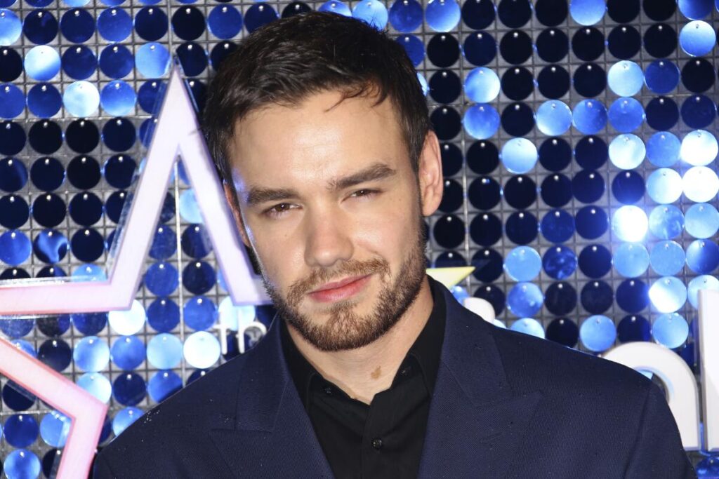 Singer Liam Payne poses for photographers in a dark suit, half-smiling to the camera