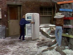 Cherie gets into an old fridge while Allen counts near a tree playing hide-and-seek on Punky Brewster