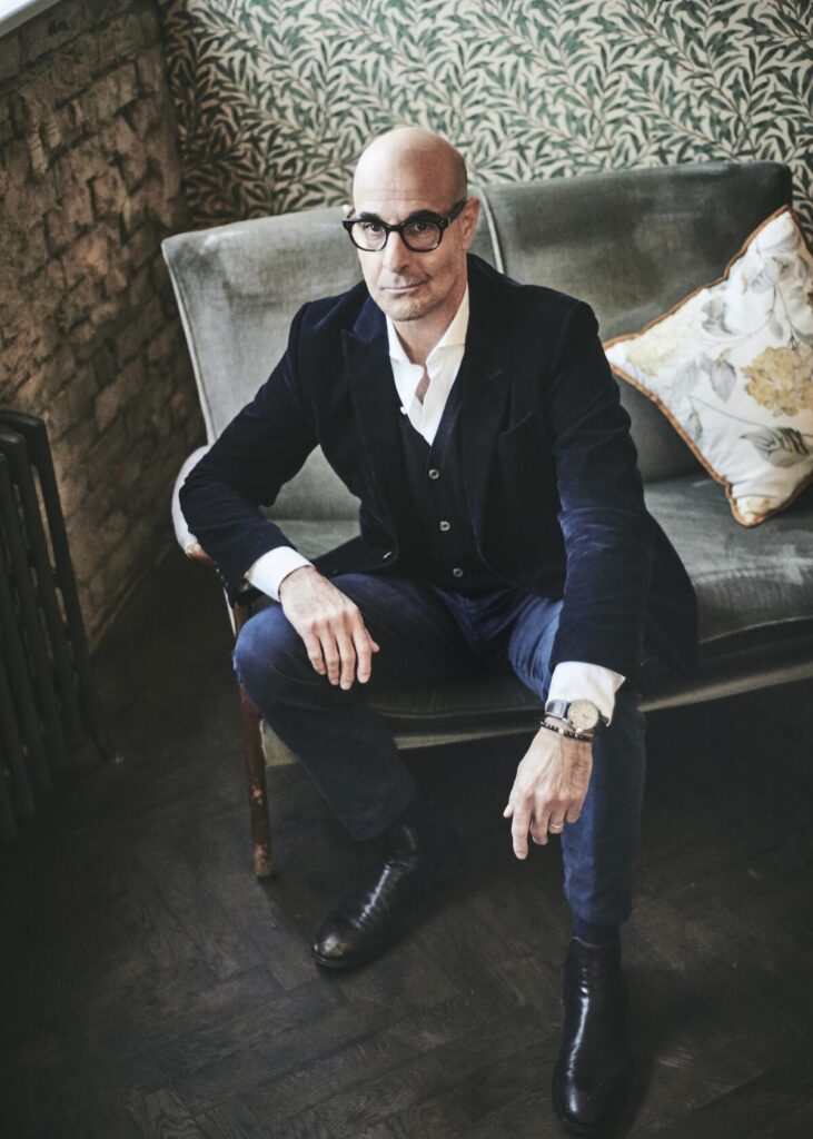 A man in a dark jacket poses in a chair.