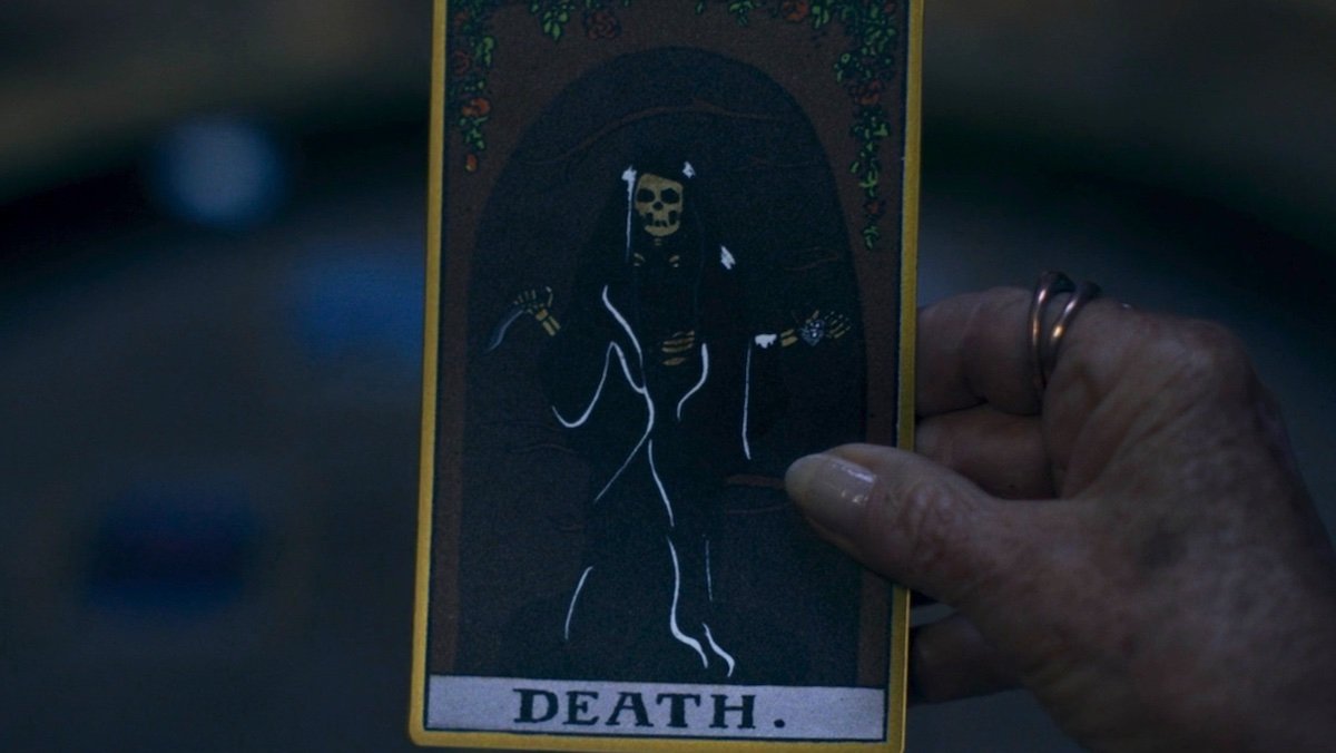 A hand holding the Death Tarot Card on Agatha All Along