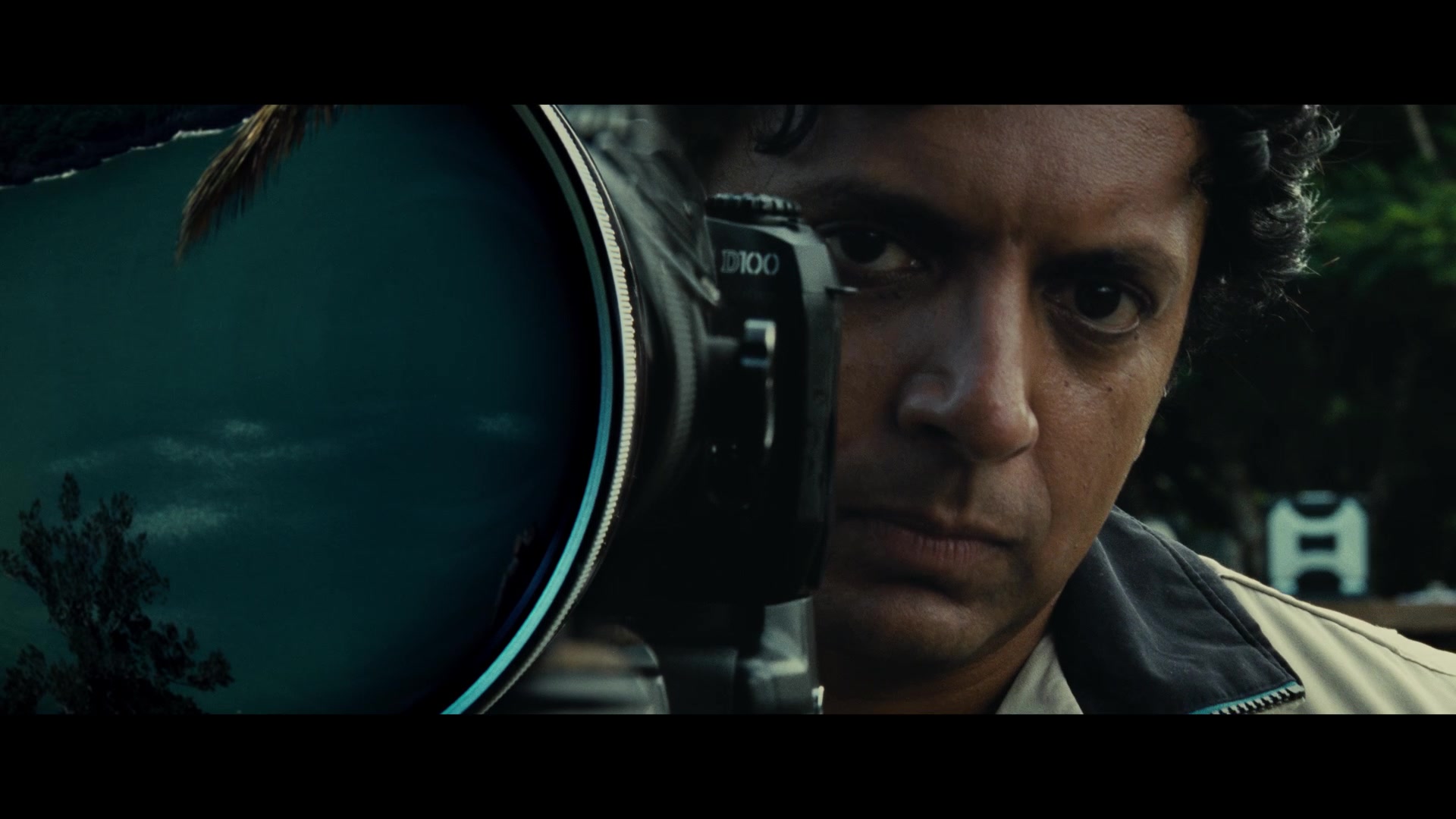 M. Night Shyamalan in Old, standing behind a camera watching the characters on the beach 