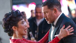 A woman in a red dress speaks to a man in a tux in Venom: The Last Dance