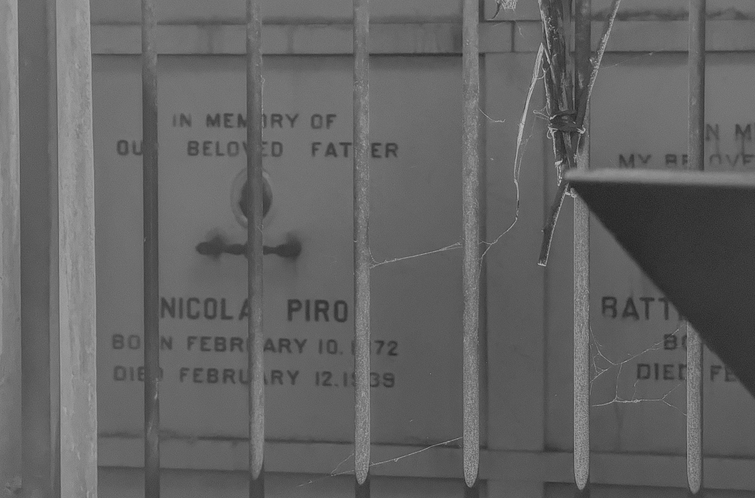 A peek at named resting places behind a metal grate from the October 3, 2024 performance of Curios in the Catacombs by Margaret Leng Tan at Green-Wood Cemetery in New York