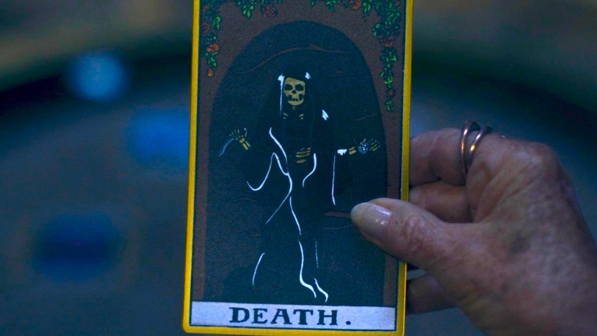 A hand holding the Death Tarot Card on Agatha All Along