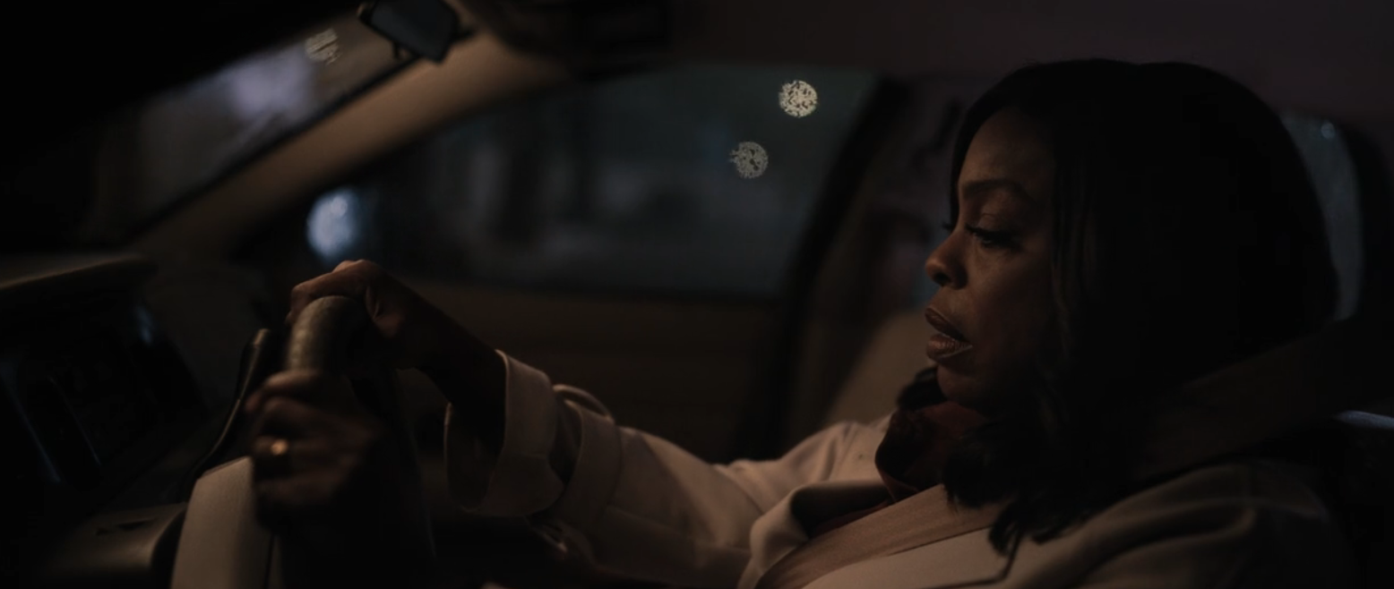 A woman drives a car at night in the rain in Grotesquerie.