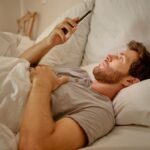 man using his smart phone in bed