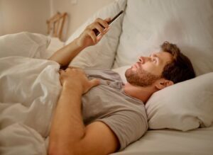 man using his smart phone in bed