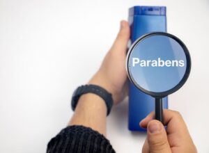 A magnifying glass over a bottle with the word 'parabens' on it