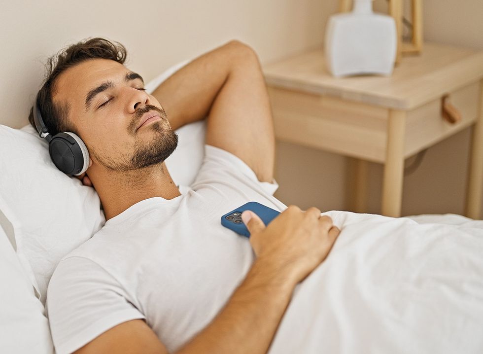 A man listening to a relaxing podcast in bed