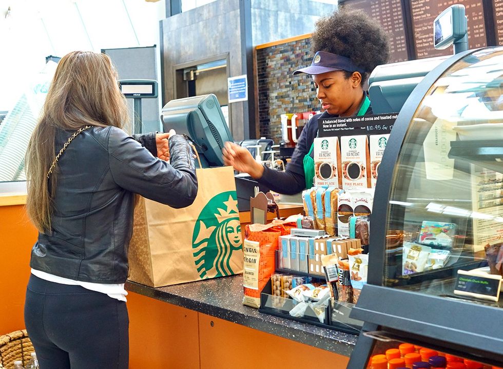 A woman paying Starbucks cashier for coffee