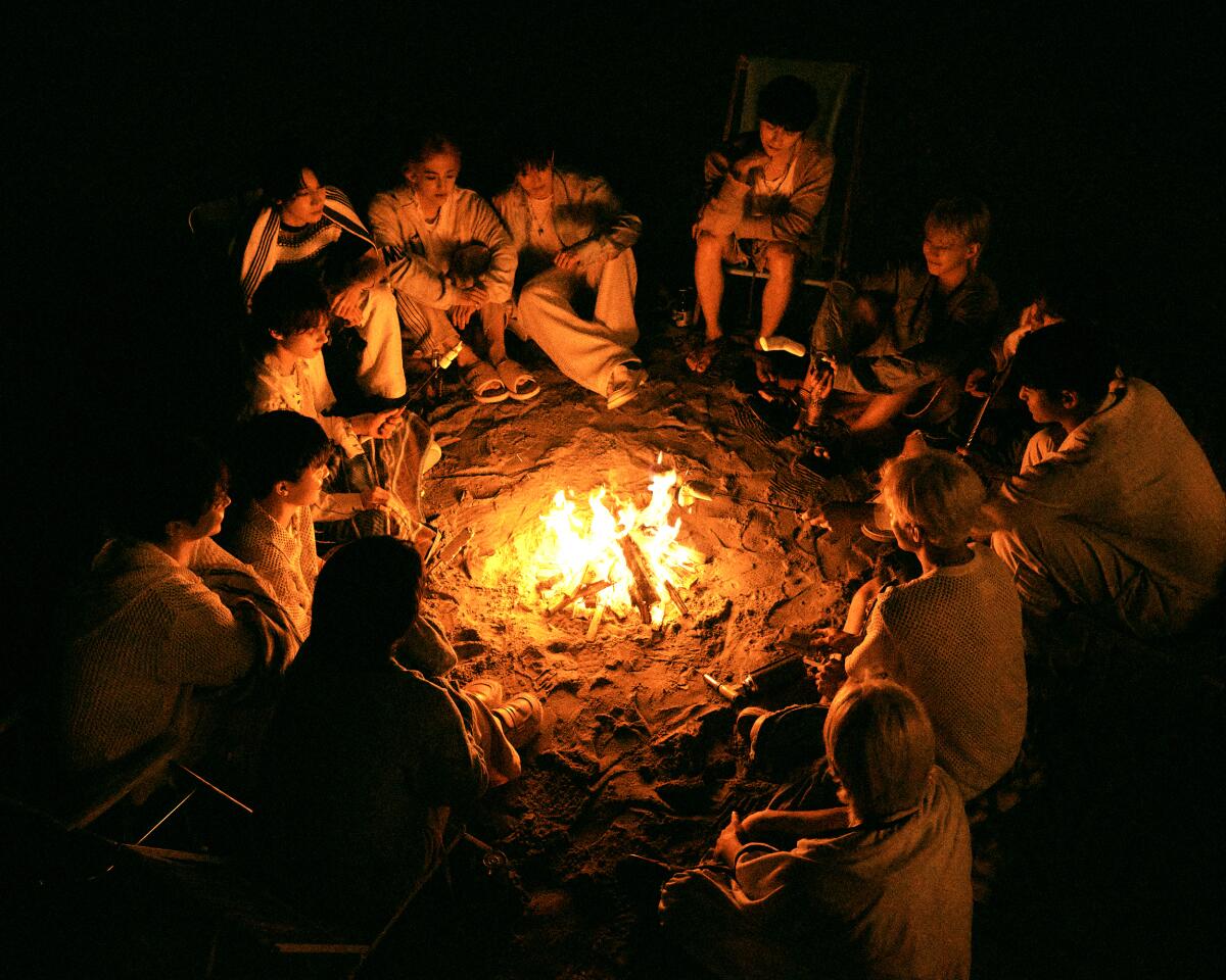 The members of Seventeen around a campfire.