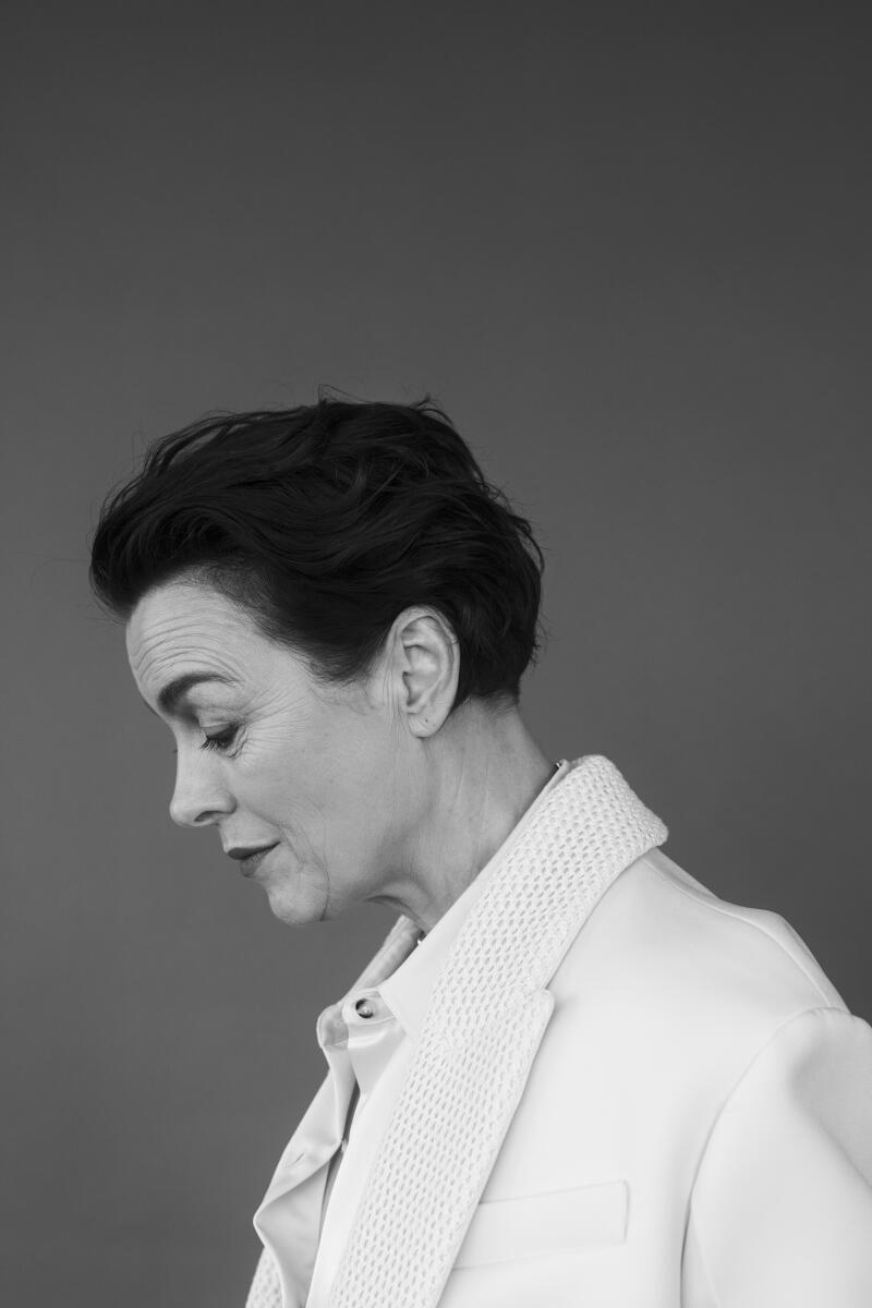 A black and white profile shot of a woman with short hair in a white suit.