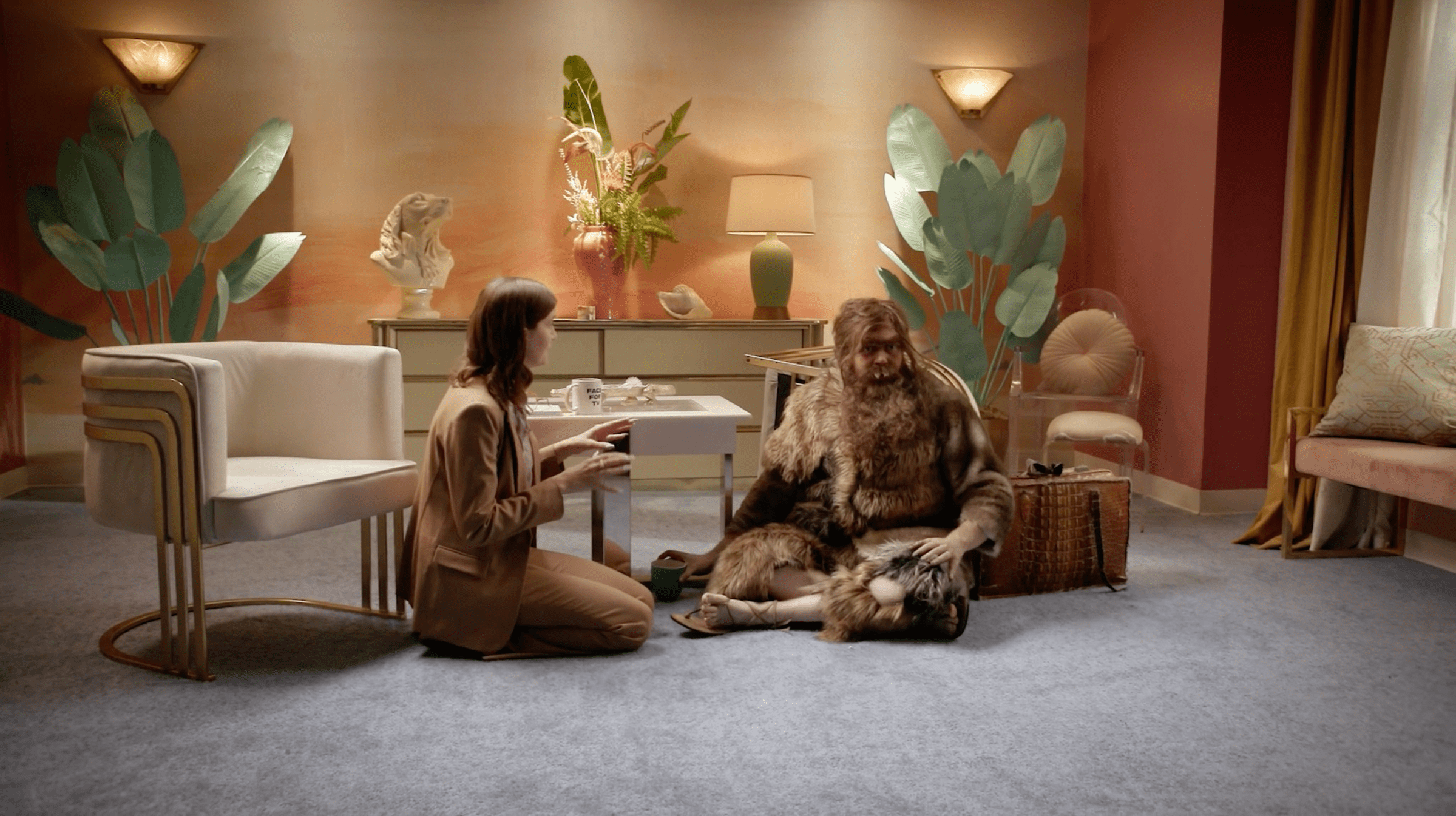 Vic Michaelis as Vic Michaelis and Brennan Lee Mulligan as Aubert in Very Important People. They’re both sitting on the floor of an interview set, Aubert is dressed in furs and has wild hair.