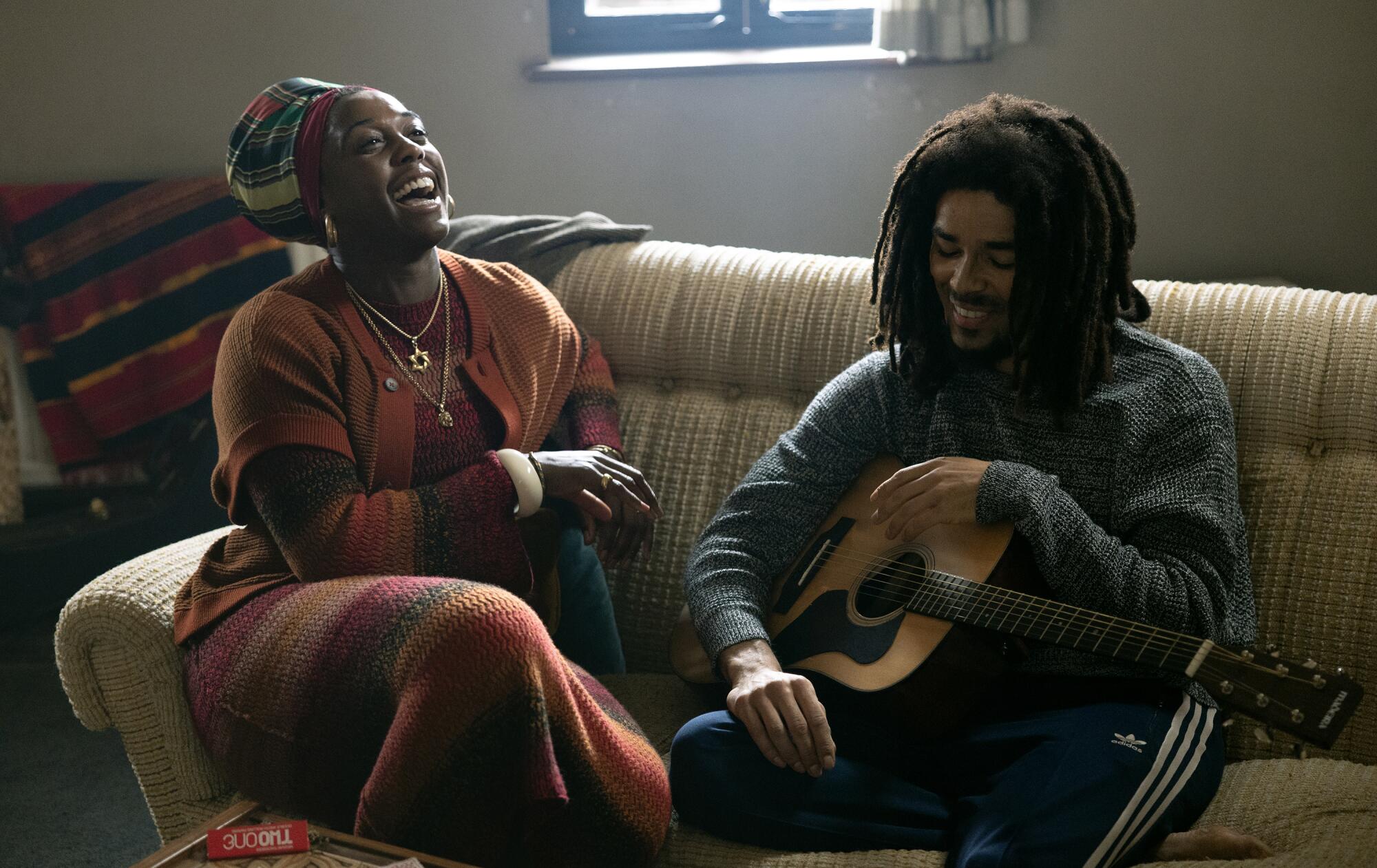 A woman and a man laugh on a sofa.