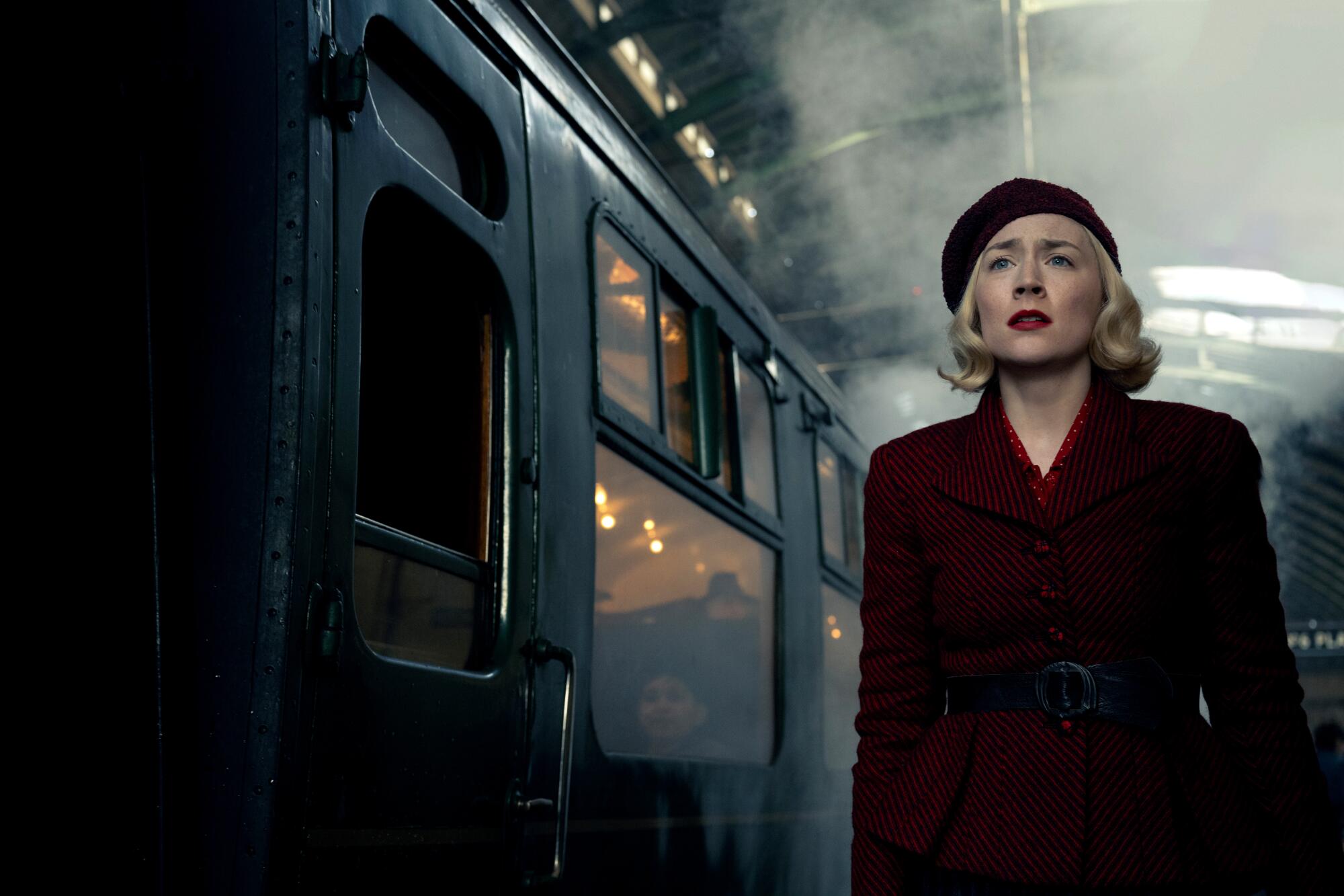 A woman in 1940s clothing looks concerned at a train station.