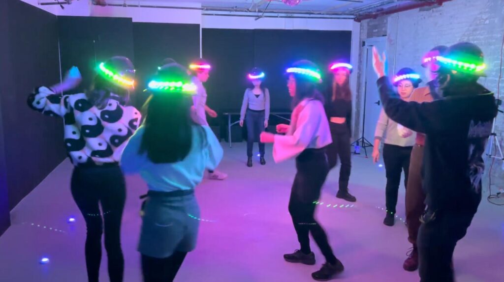 A group of young adults wearing hats with LED lights on them.