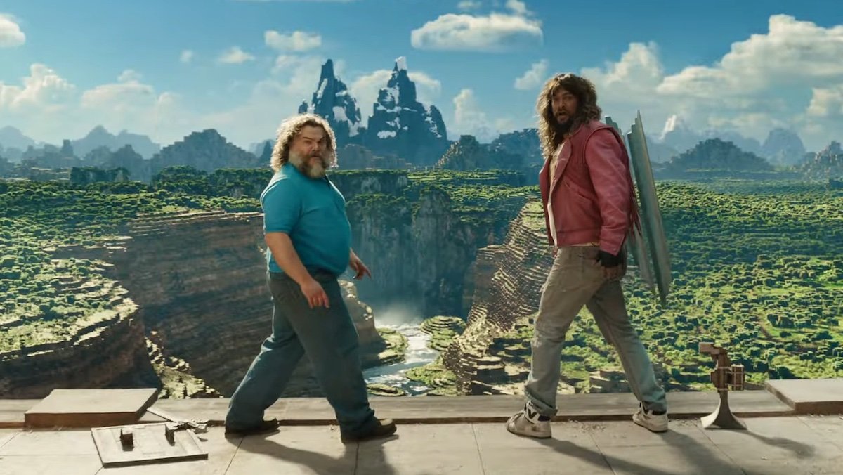 Jack Black and Jason Momoa both turn around to look back from the edge of a cliff in A Minecraft movie